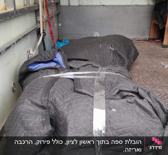 שקי העברה עטופים בשמיכות בתוך משאית הובלה